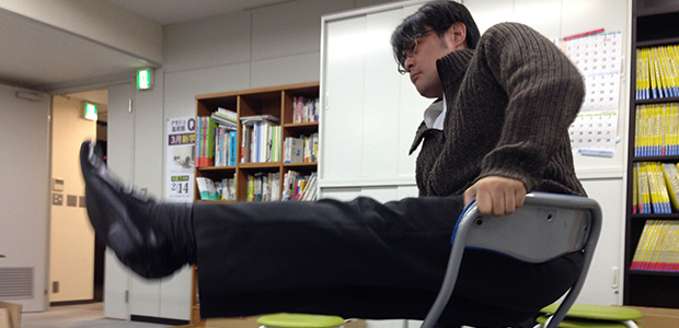椅子の上で何かやる池村氏